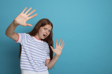 Photo of Teenage girl suffering from panic attack on light blue background. Space for text