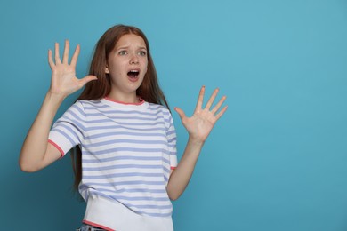 Photo of Teenage girl suffering from panic attack on light blue background. Space for text