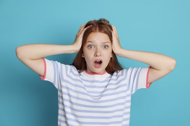 Photo of Teenage girl suffering from panic attack on light blue background
