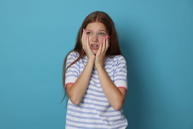 Photo of Teenage girl suffering from panic attack on light blue background