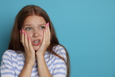 Photo of Teenage girl suffering from panic attack on light blue background. Space for text