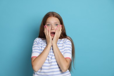 Photo of Teenage girl suffering from panic attack on light blue background