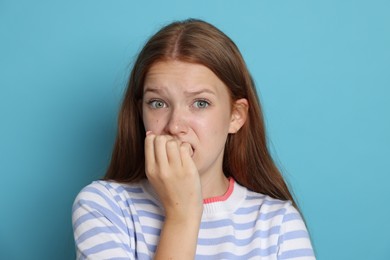 Photo of Teenage girl suffering from panic attack on light blue background