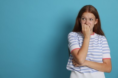 Photo of Teenage girl suffering from panic attack on light blue background. Space for text