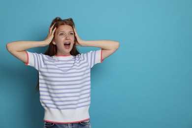 Photo of Teenage girl suffering from panic attack on light blue background. Space for text