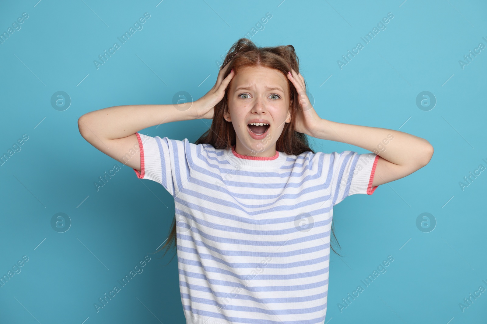 Teenage girl suffering from panic attack on light blue background Photo of Teenage girl suffering from panic attack on light blue background