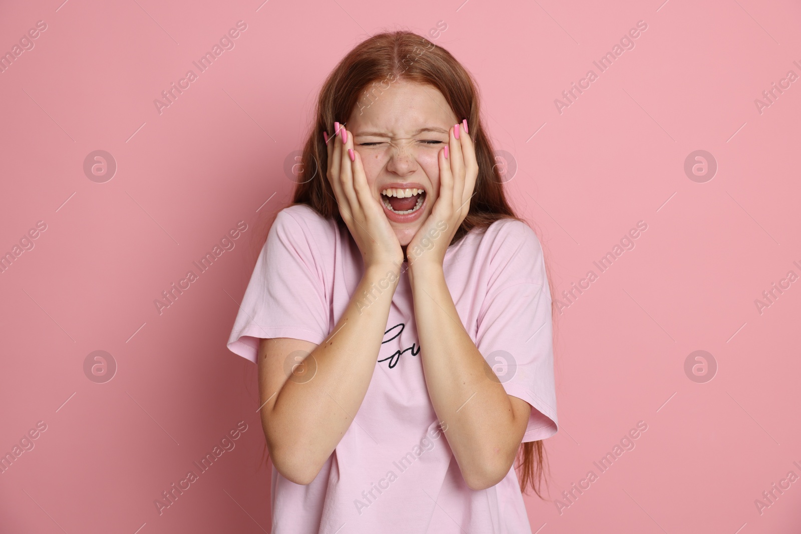 Photo of Teenage girl suffering from panic attack on pink background