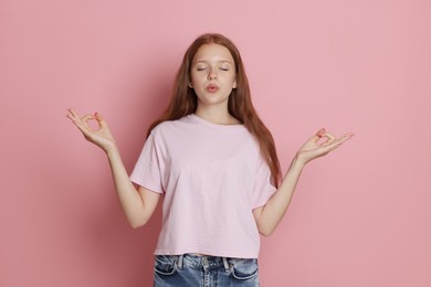 Photo of Teenage girl meditating on pink background. Way to stop panic attack