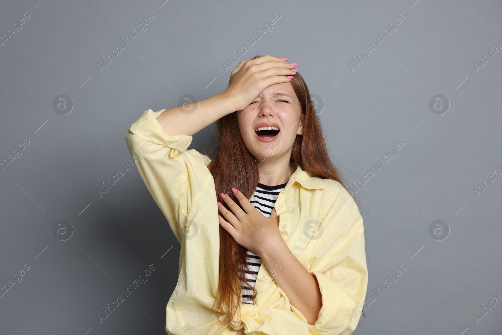 Photo of Teenage girl suffering from panic attack on grey background