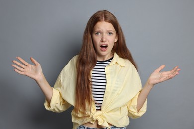 Photo of Teenage girl suffering from panic attack on grey background