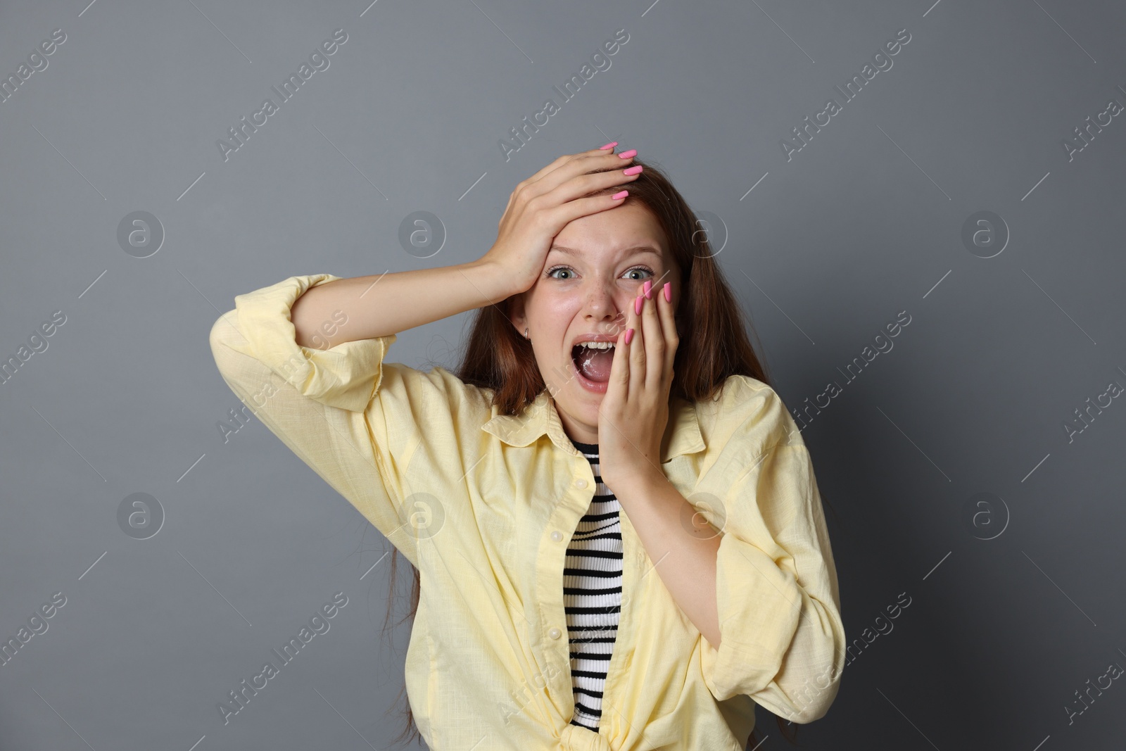 Teenage girl suffering from panic attack on grey background Photo of Teenage girl suffering from panic attack on grey background