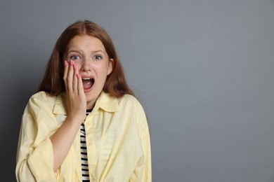 Photo of Teenage girl suffering from panic attack on grey background. Space for text