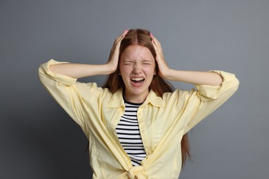 Photo of Teenage girl suffering from panic attack on grey background