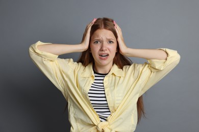 Photo of Teenage girl suffering from panic attack on grey background