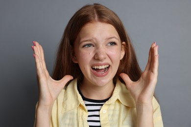 Photo of Teenage girl suffering from panic attack on grey background