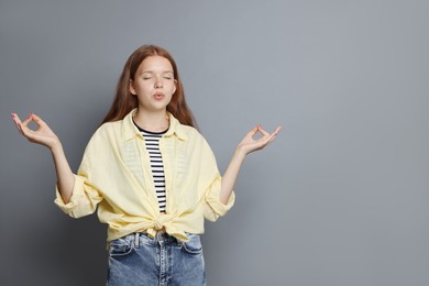 Photo of Teenage girl meditating on grey background, space for text. Way to stop panic attack
