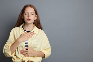 Photo of Teenage girl deep breathing on grey background, space for text. Way to stop panic attack