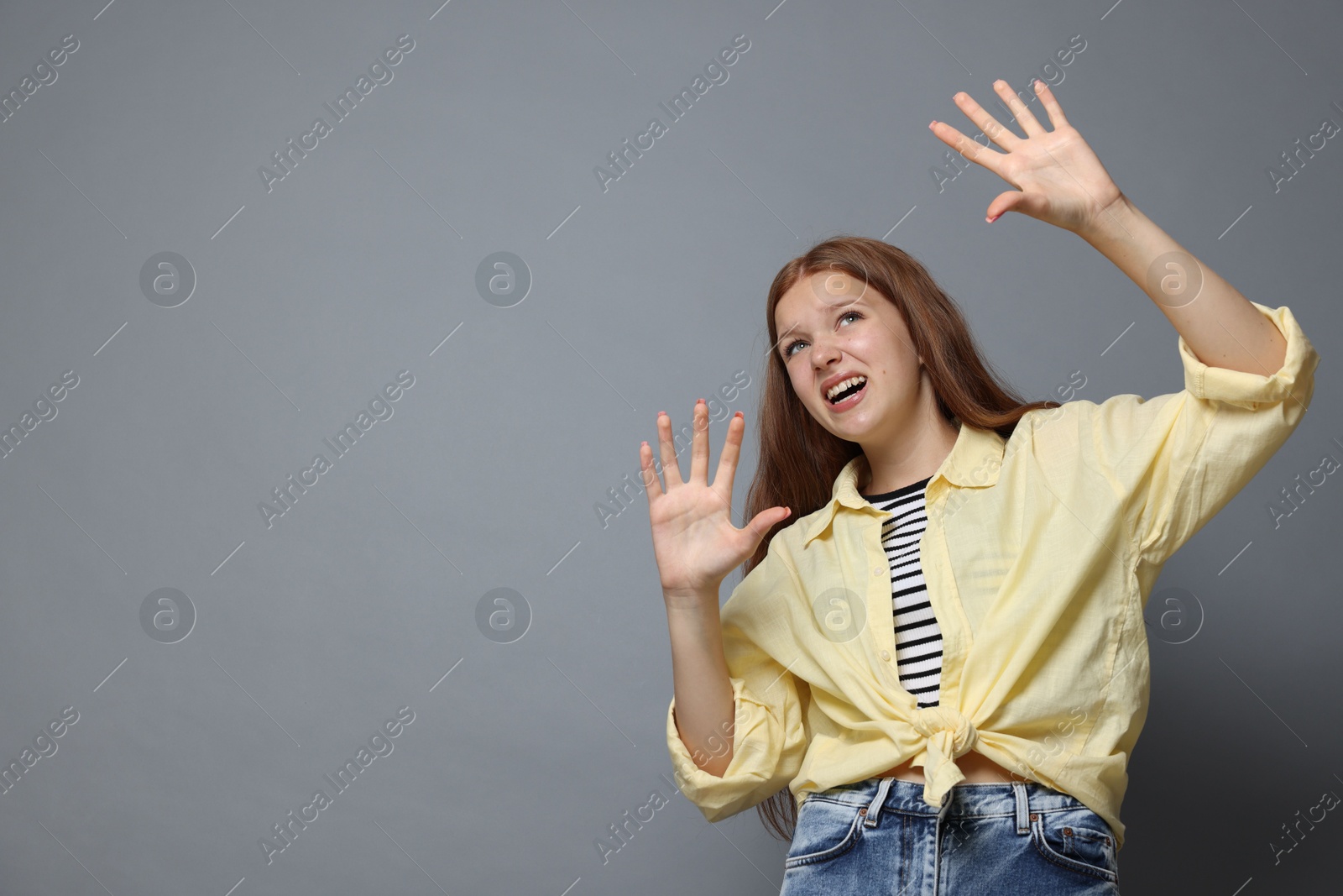 Teenage girl suffering from panic attack on grey background. Space for text Photo of Teenage girl suffering from panic attack on grey background. Space for text