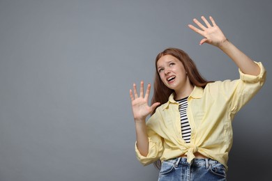 Photo of Teenage girl suffering from panic attack on grey background. Space for text