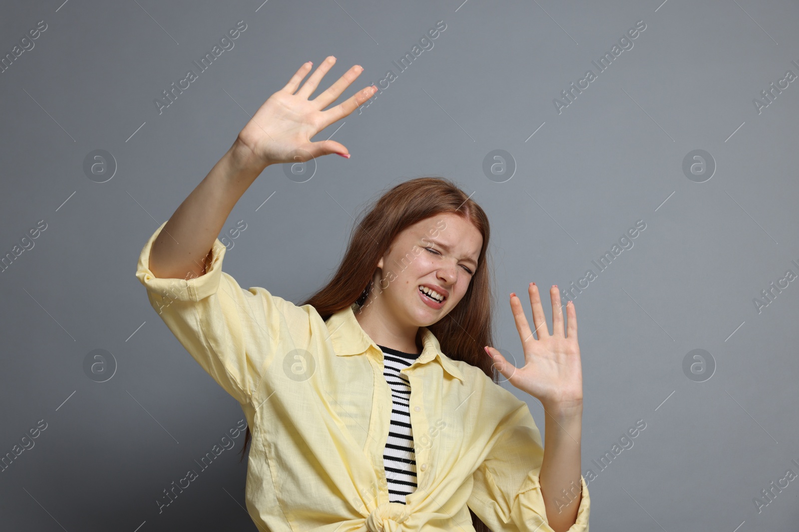Teenage girl suffering from panic attack on grey background Photo of Teenage girl suffering from panic attack on grey background