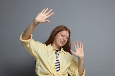 Photo of Teenage girl suffering from panic attack on grey background