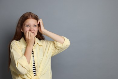 Photo of Teenage girl suffering from panic attack on grey background. Space for text