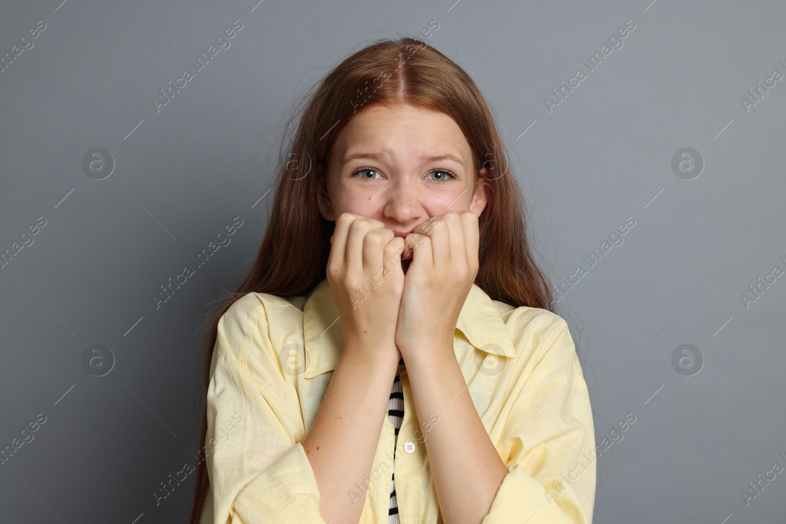 Teenage girl suffering from panic attack on grey background Photo of Teenage girl suffering from panic attack on grey background