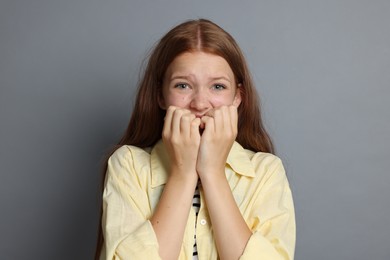 Photo of Teenage girl suffering from panic attack on grey background