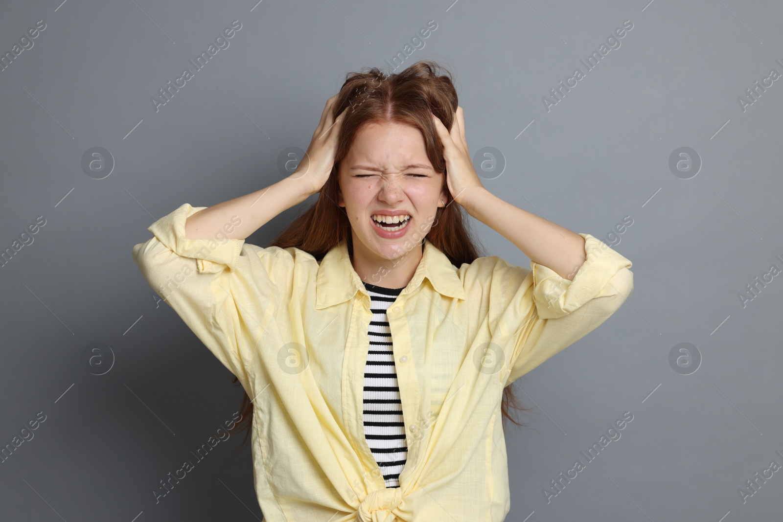 Teenage girl suffering from panic attack on grey background Photo of Teenage girl suffering from panic attack on grey background