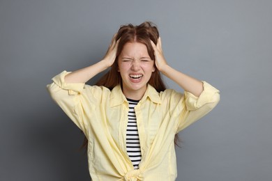 Photo of Teenage girl suffering from panic attack on grey background
