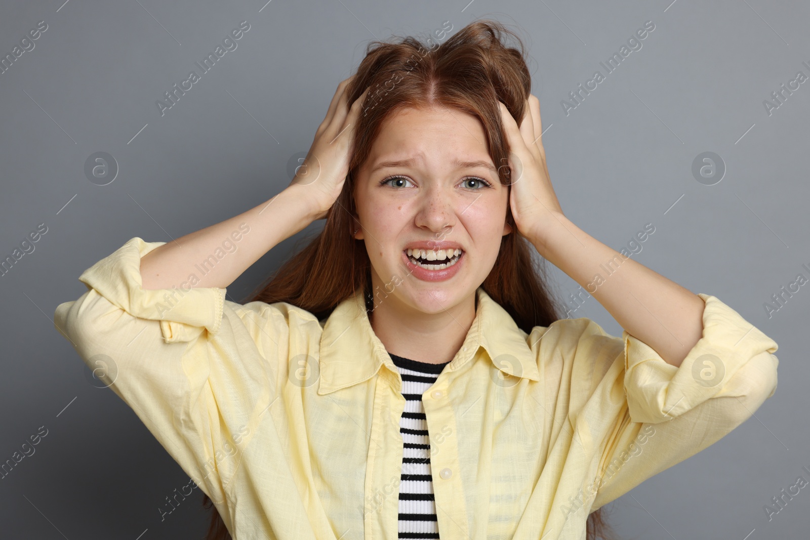 Teenage girl suffering from panic attack on grey background Photo of Teenage girl suffering from panic attack on grey background