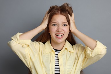 Photo of Teenage girl suffering from panic attack on grey background