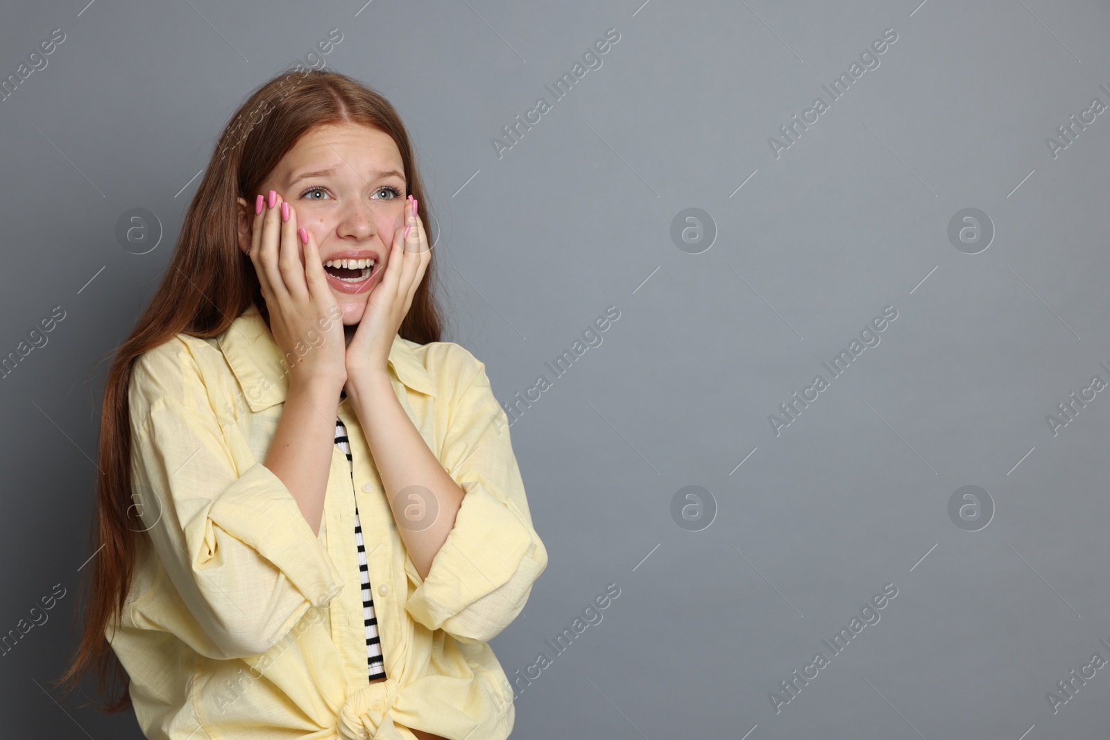 Teenage girl suffering from panic attack on grey background. Space for text Photo of Teenage girl suffering from panic attack on grey background. Space for text