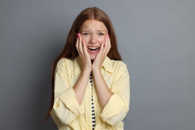 Photo of Teenage girl suffering from panic attack on grey background