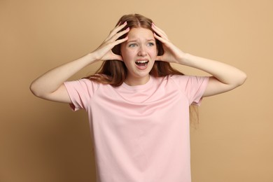 Photo of Teenage girl suffering from panic attack on beige background