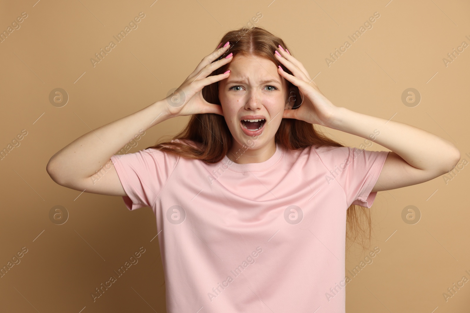 Teenage girl suffering from panic attack on beige background Photo of Teenage girl suffering from panic attack on beige background