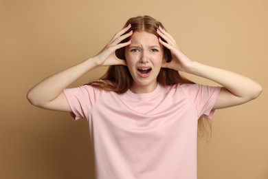 Photo of Teenage girl suffering from panic attack on beige background