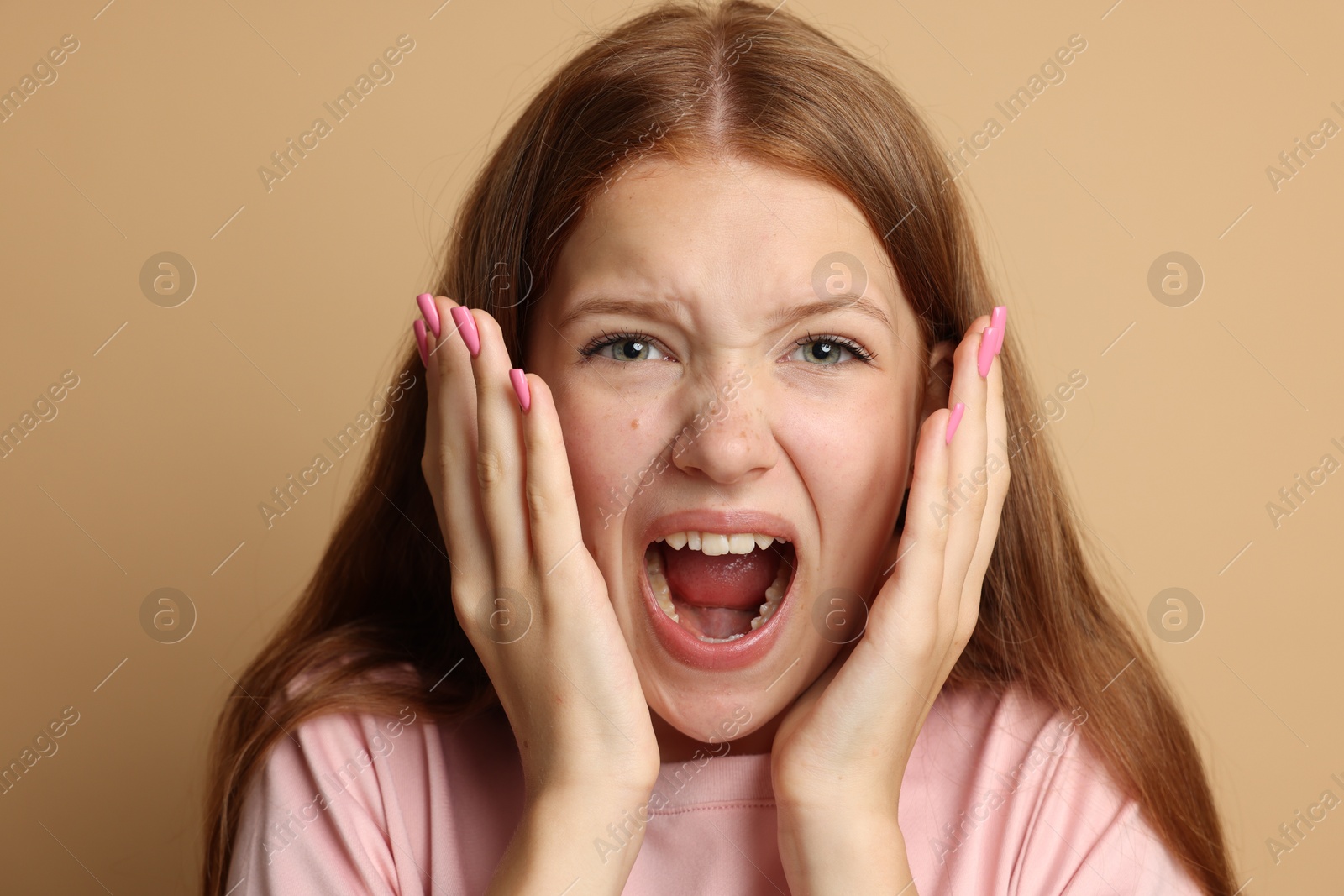 Teenage girl suffering from panic attack on beige background Photo of Teenage girl suffering from panic attack on beige background