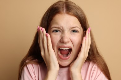Photo of Teenage girl suffering from panic attack on beige background