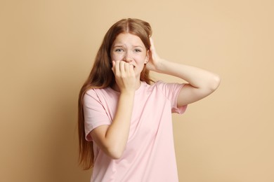 Photo of Teenage girl suffering from panic attack on beige background
