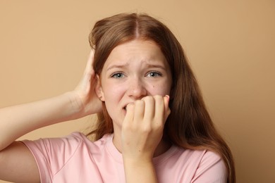 Photo of Teenage girl suffering from panic attack on beige background
