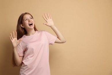 Photo of Teenage girl suffering from panic attack on beige background. Space for text
