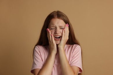 Photo of Teenage girl suffering from panic attack on beige background