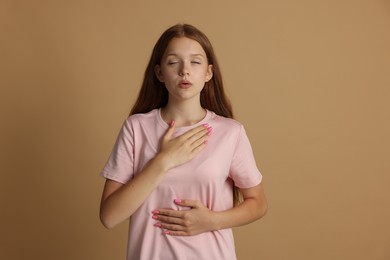 Photo of Teenage girl deep breathing on beige background. Way to stop panic attack