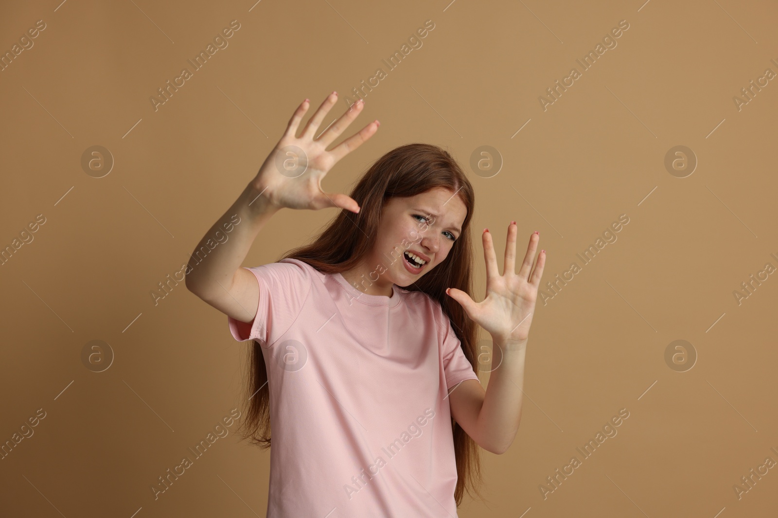 Photo of Teenage girl suffering from panic attack on beige background