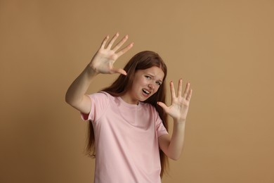 Photo of Teenage girl suffering from panic attack on beige background