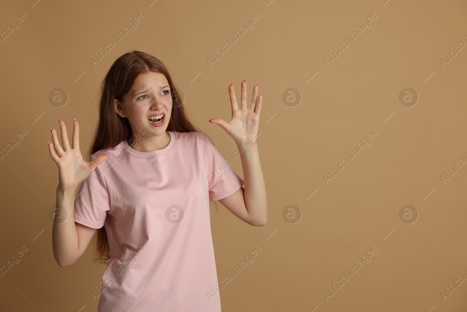 Teenage girl suffering from panic attack on beige background. Space for text Photo of Teenage girl suffering from panic attack on beige background. Space for text