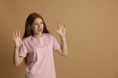 Photo of Teenage girl suffering from panic attack on beige background. Space for text