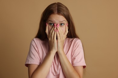 Photo of Teenage girl suffering from panic attack on beige background