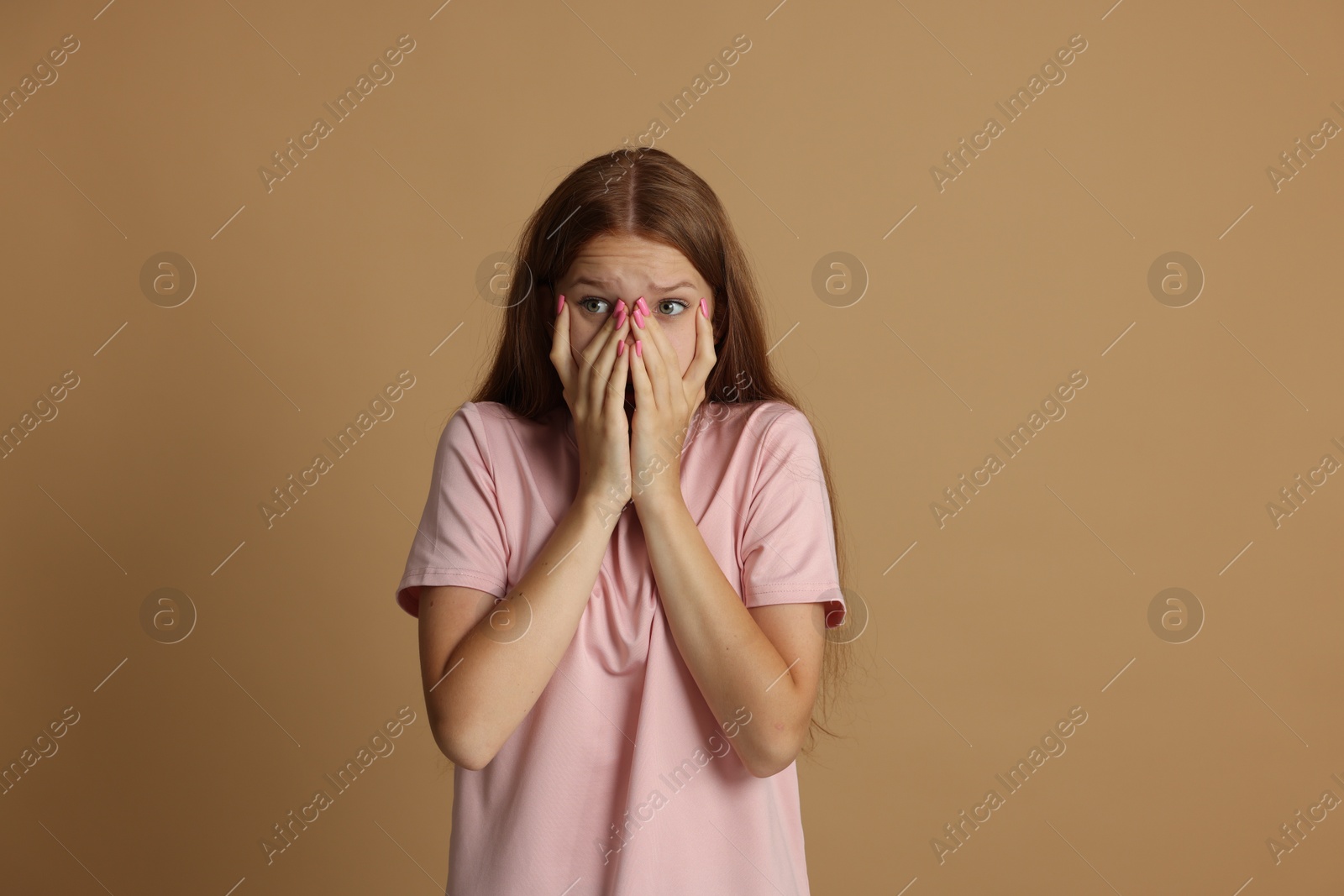 Teenage girl suffering from panic attack on beige background Photo of Teenage girl suffering from panic attack on beige background